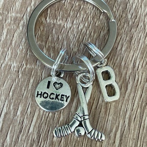 May include: Silver keyring with a hockey stick charm, a charm that says "I love hockey", and a letter "B" charm.
