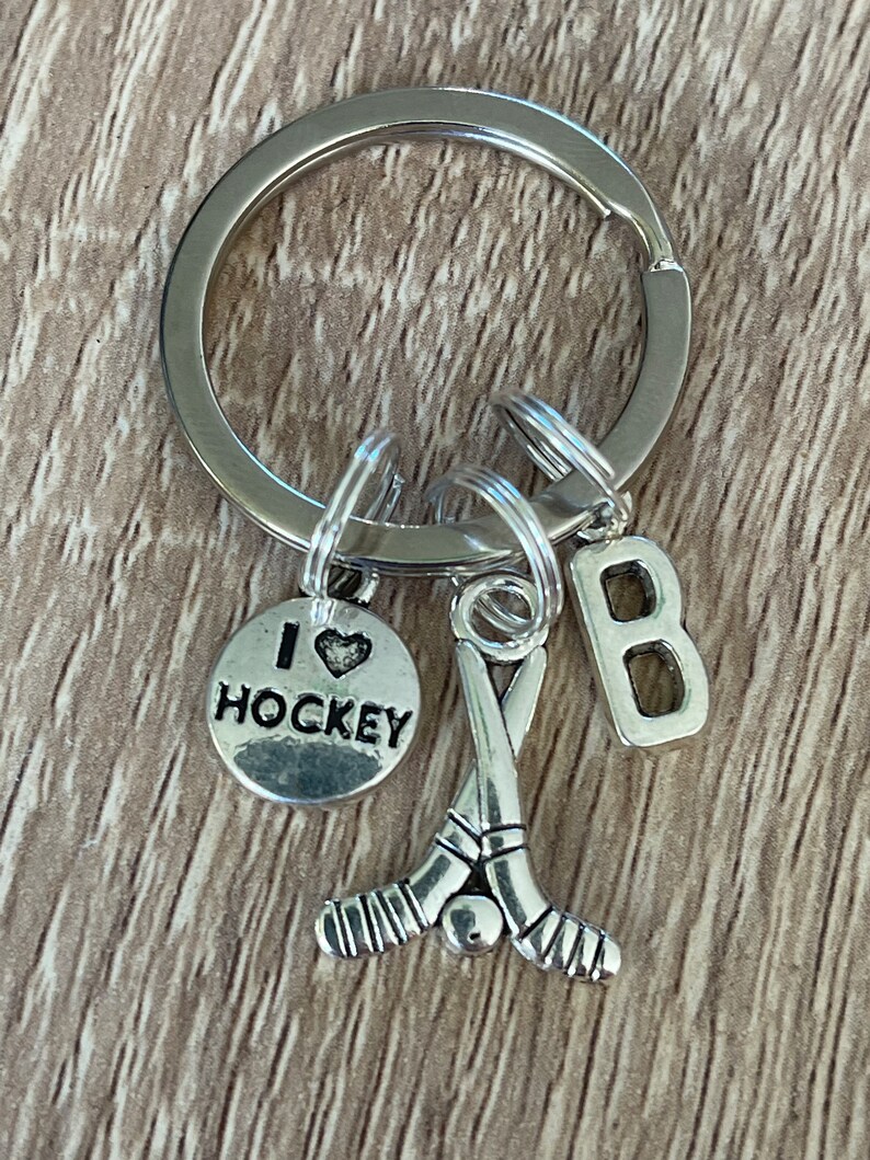 May include: Silver keyring with a hockey stick charm, a charm that says "I love hockey", and a letter "B" charm.