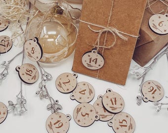 May include: Wooden Christmas advent calendar ornaments with numbers 2, 4, 5, 6, 8, 9, 14, 15, 17, 18, 19, and 27. The ornaments are decorated with stars and a small sprig of wheat.