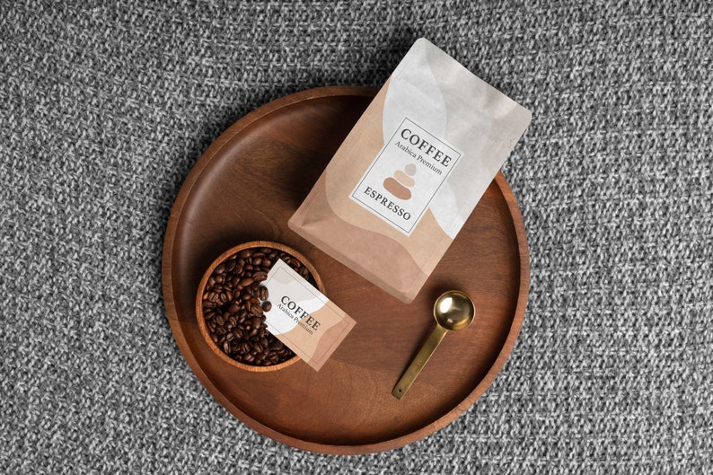 Puede incluir: Vista superior de una bandeja de madera con art&iacute;culos relacionados con el caf&eacute;. Una bolsa de caf&eacute; espresso y un paquete peque&ntilde;o est&aacute;n en la bandeja, junto con un peque&ntilde;o cuenco de madera lleno de granos de caf&eacute; y una cuchara dorada. El texto "COFFEE Espresso" es visible.