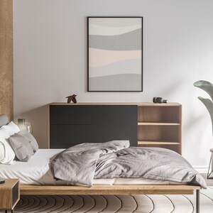 Puede incluir: Un dormitorio moderno con una cama de madera, una mesita de noche y una c&oacute;moda. Una obra de arte abstracta enmarcada cuelga sobre la c&oacute;moda. Una gran planta en maceta est&aacute; al lado de la cama. La ropa de cama es gris.