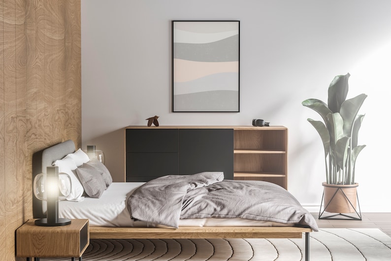 Puede incluir: Un dormitorio moderno con una cama de madera, una mesita de noche y una c&oacute;moda. Una obra de arte abstracta enmarcada cuelga sobre la c&oacute;moda. Una gran planta en maceta est&aacute; al lado de la cama. La ropa de cama es gris.