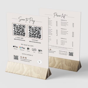 May include: A white sign with a black and white QR code, the text "Scan to Pay", and payment options including Cash App, Venmo, Apple Pay, Google Pay, PayPal, Cash, and Credit Card. The sign also includes a QR code for social media and the text "Lets Connect". The sign is on a wooden stand.