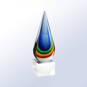 May include: A glass award in the shape of a teardrop with layers of blue, green, and orange glass. The award sits on a clear glass base.