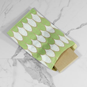 May include: A green and white patterned gift bag with a brown cardboard box inside. The bag has a white feather design on a green background.