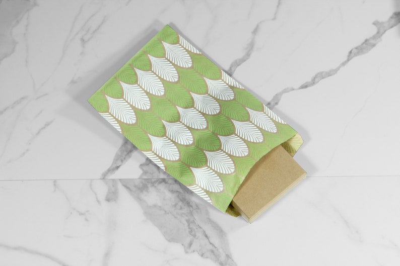 May include: A green and white patterned gift bag with a brown cardboard box inside. The bag has a white feather design on a green background.