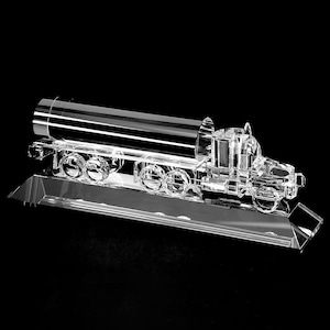 May include: A crystal clear glass sculpture of a tanker truck. The truck is on a clear glass base. The sculpture is a representation of a tanker truck.