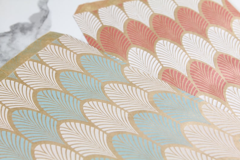 K&ouml;nnte beinhalten: Zwei Bl&auml;tter braunes Geschenkpapier mit einem wei&szlig;en und blauen geometrischen Muster. Das Muster ist ein sich wiederholendes Design aus stilisierten Federn.