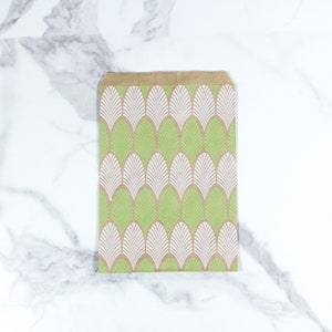 K&ouml;nnte beinhalten: Eine braune Papiert&uuml;te mit einem geometrischen Muster in Gr&uuml;n und Wei&szlig;. Das Muster zeigt ein sich wiederholendes Design aus stilisierten Bl&auml;ttern.