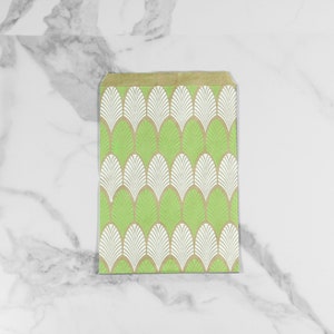 May include: A green and white patterned paper gift bag with a geometric design. The bag is made of brown paper and has a white and green pattern of overlapping leaves.