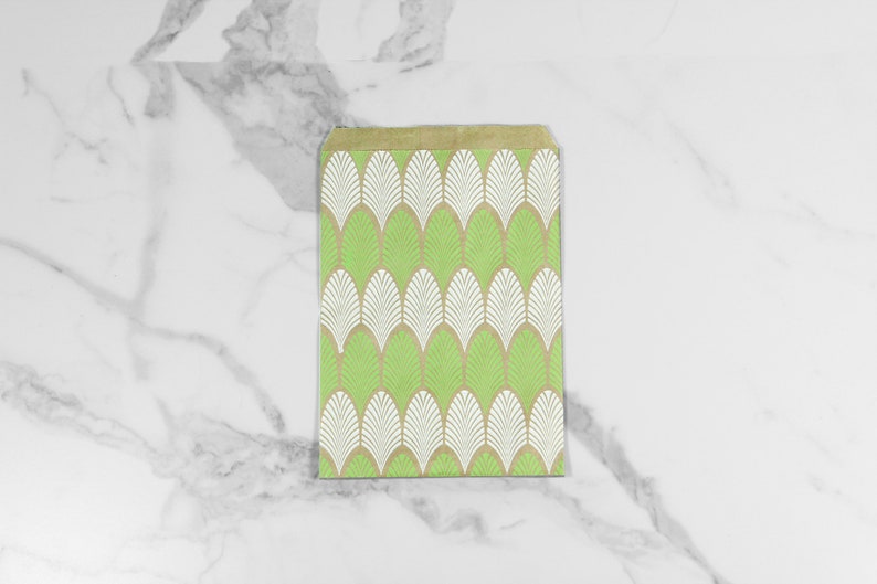 May include: A green and white patterned paper gift bag with a geometric design. The bag is made of brown paper and has a white and green pattern of overlapping leaves.