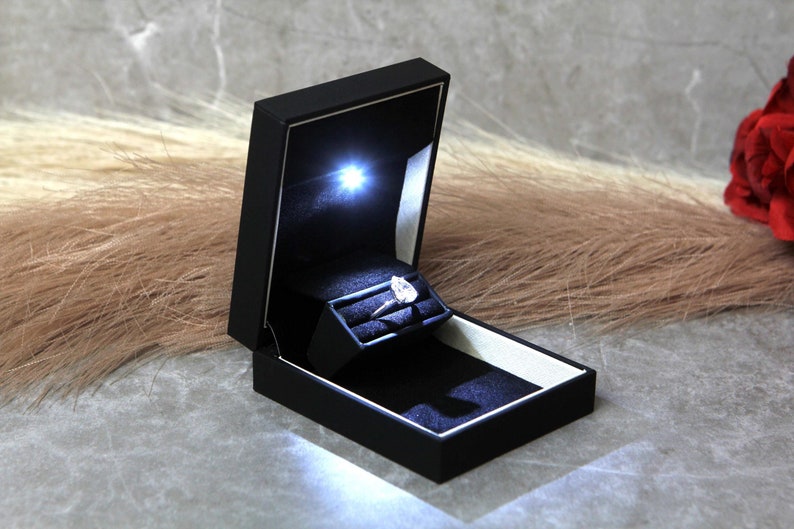 slim black ring box with led light and pear shaped diamond engagement ring