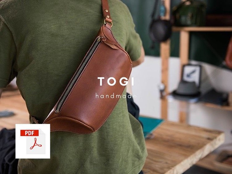 May include: A brown leather fanny pack with a zipper closure and a strap. The bag is worn by a person and has the text "TOGI handmade" on the front.