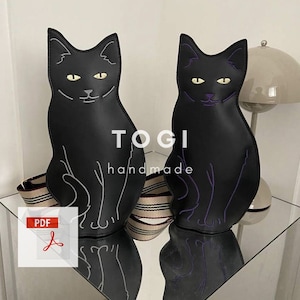 Puede incluir: Dos bolsos negros con forma de gato con una correa a rayas. Los bolsos tienen detalles bordados y el texto "TOGI handmade" es visible. Un icono PDF está en la esquina inferior izquierda de la imagen.