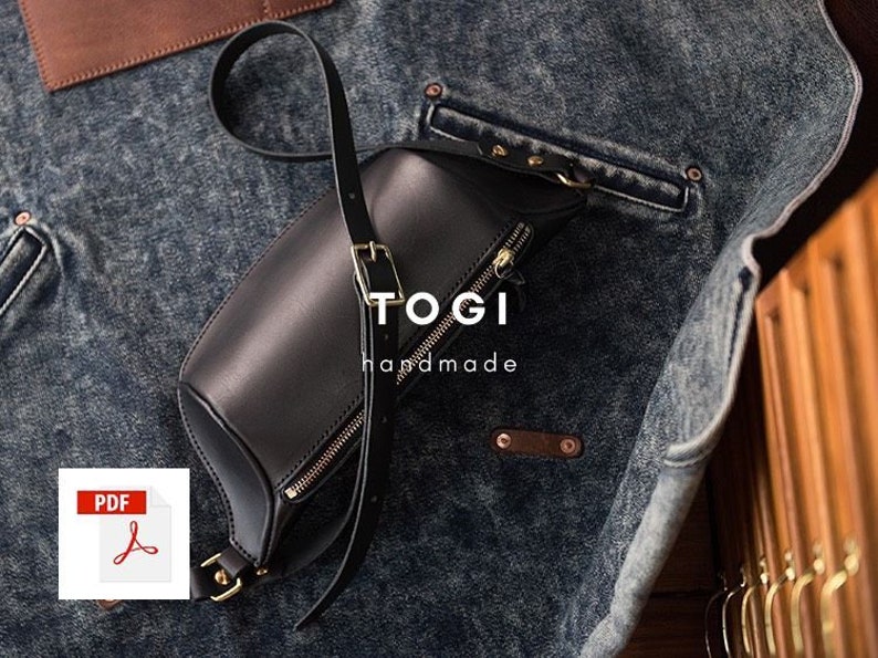 May include: A black leather crossbody bag with a gold zipper and a gold buckle. The bag is on a denim background and has the text "TOGI handmade" on it.