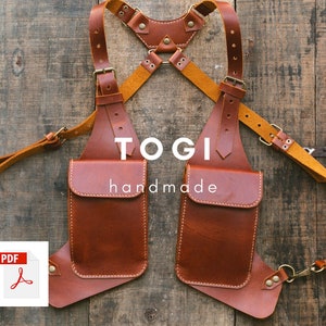 May include: Brown leather chest rig with two pockets and adjustable straps. The rig is labeled "TOGI handmade".