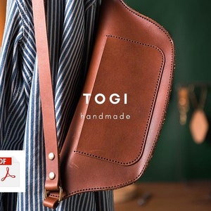 May include: A brown leather crossbody bag with a flap closure and a strap. The bag has the text "TOGI handmade" on the front.