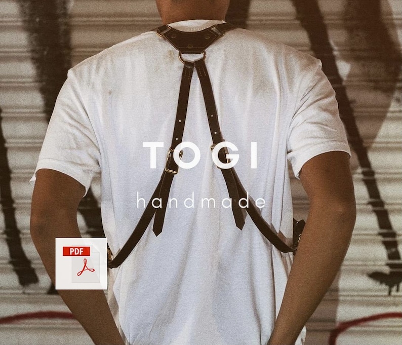 May include: A person wearing a white t-shirt with a black leather harness. The harness has a gold ring and the text "TOGI handmade" is printed on the front.