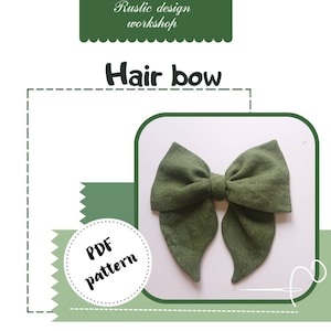Pode incluir: Um laço de cabelo verde-oliva feito à mão com tecido texturizado. A imagem inclui o texto "Hair bow" e "PDF pattern", com "Rustic design workshop" no topo. O laço está centrado num fundo branco.