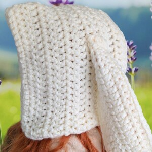 May include: A white crocheted hat with a long pointed crown and a single ear flap.