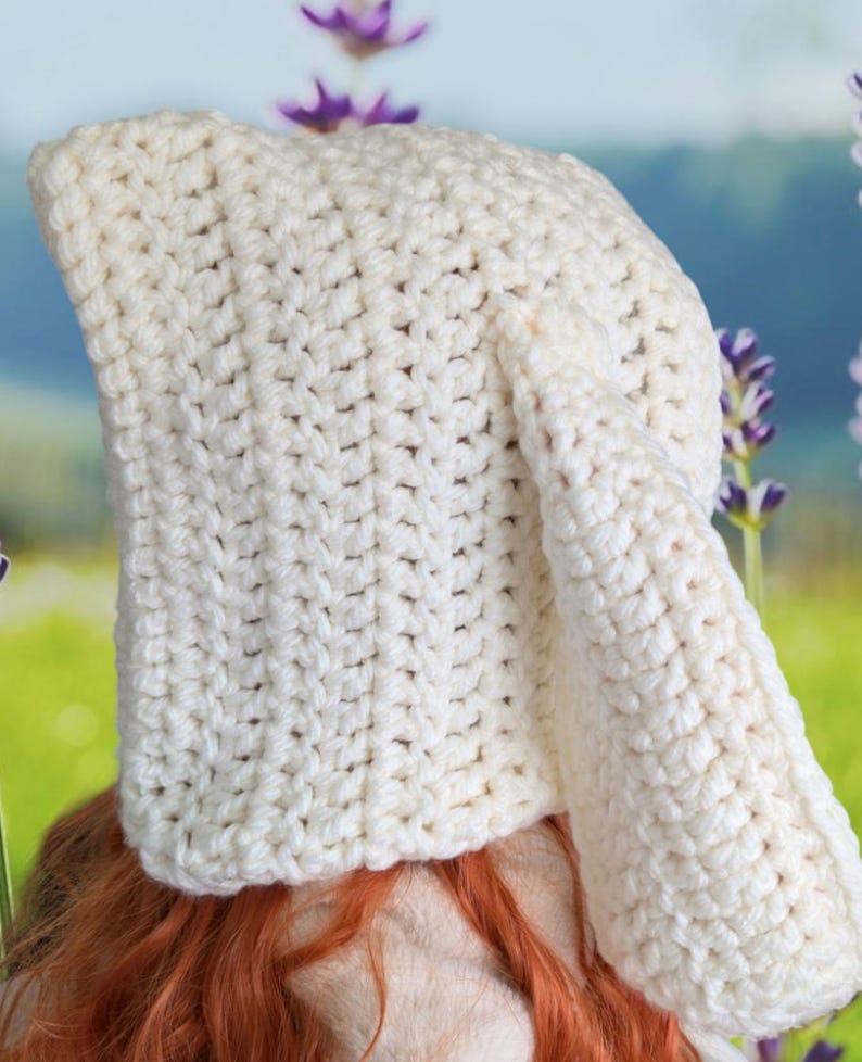 May include: A white crocheted hat with a long pointed crown and a single ear flap.
