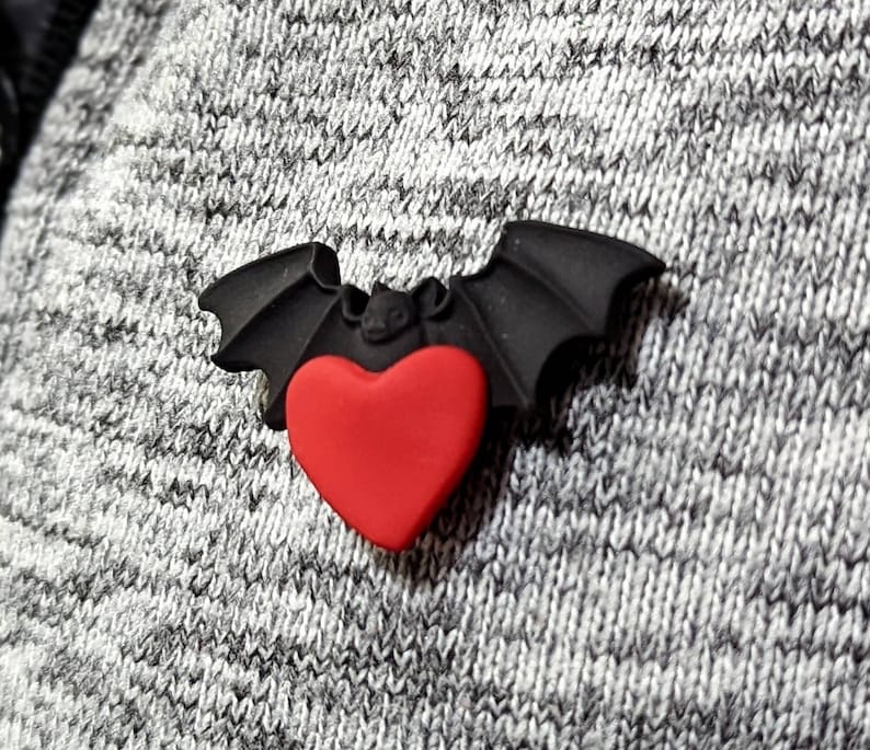 May include: A black bat with a red heart in the centre. The bat is made of rubber and has a glossy finish.