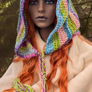 May include: A colourful crocheted hooded scarf with a long braided tassel. The scarf is made with a variety of colours, including pink, blue, green, and purple.