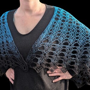 May include: A blue and black crocheted shawl with a gradient effect. The shawl is draped over the shoulders, showcasing an open, lacy design. The color transitions from a bright blue to a deep black.