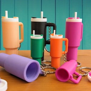 May include: A set of eight colorful, miniature, plastic cups with lids and straws. The cups are attached to keychains and are designed to look like to-go coffee cups.