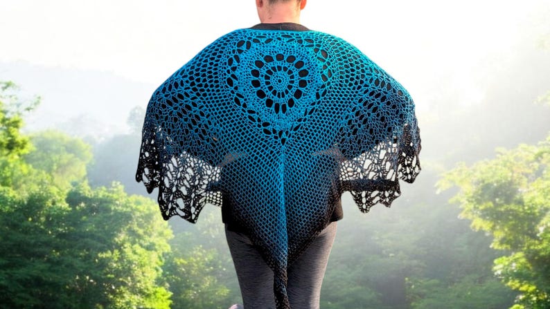 May include: A blue and black crocheted shawl with a circular design in the center. The shawl has a gradient effect, transitioning from blue to black. The open weave design is visible, and the shawl is worn outdoors.