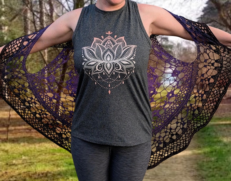 May include: A dark grey vest top featuring a white and pink lotus flower design. A black and purple crocheted shawl is draped over the shoulders. The shawl has an openwork pattern.
