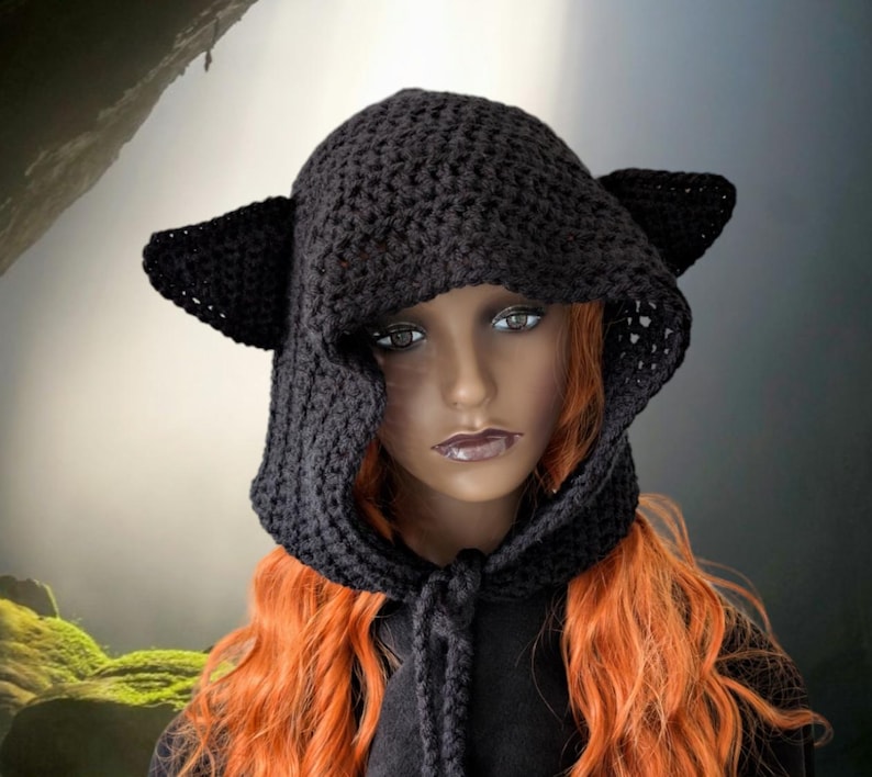 Puede incluir: Sombrero de punto negro con capucha y orejas de gato. El sombrero est&aacute; hecho de un hilo suave y c&aacute;lido y tiene una capucha larga y fluida. Las orejas est&aacute;n unidas a la parte superior de la capucha y tienen unos 7,5 cm de largo.
