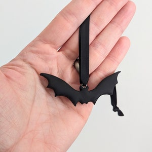 May include: Black bat-shaped ornament with a black ribbon for hanging.