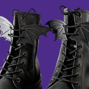 May include: A pair of black leather boots with bat wing shoe charms. The charms are silver and black.