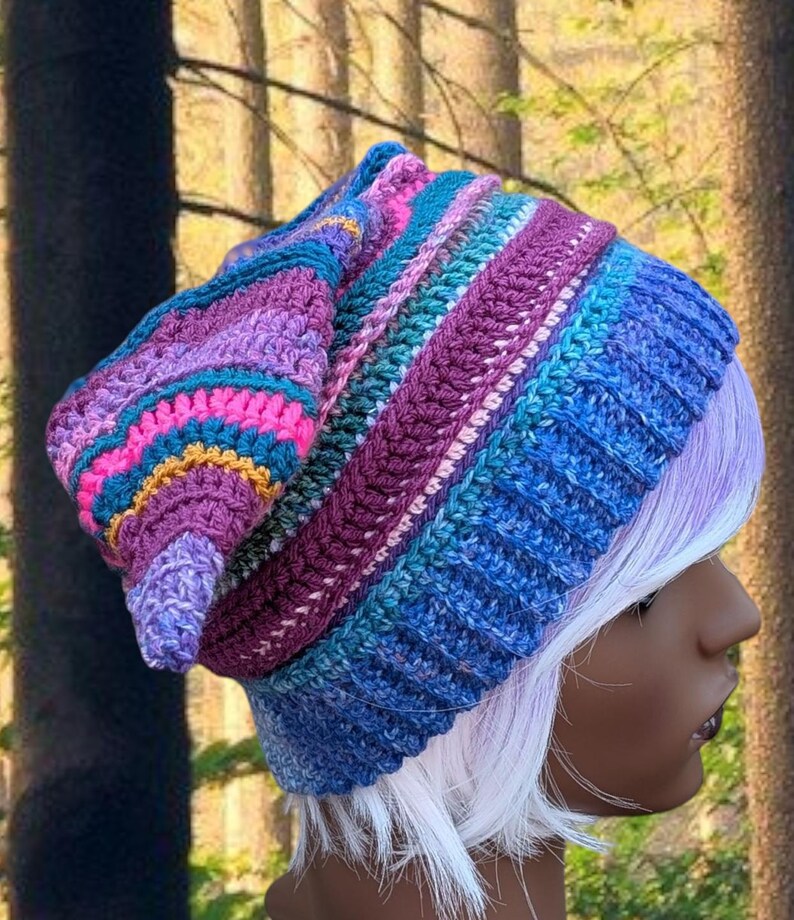 Może przedstawiać: Kolorowa, ręcznie robiona czapka typu beanie w odcieniach niebieskiego, fioletowego, r&oacute;żowego i turkusowego. Czapka ma prążkowany wz&oacute;r i luźny kr&oacute;j, idealna do dodania odrobiny koloru do każdego stroju. Czapka to przytulny i stylowy dodatek.