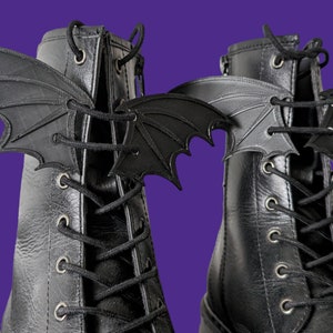 May include: A pair of black leather boots with black bat-shaped lace charms attached to the laces.