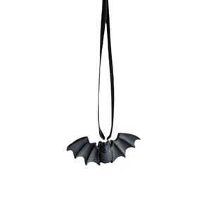 Puede incluir: Un amuleto negro en forma de murci&eacute;lago cuelga de una cuerda negra. El amuleto es una decoraci&oacute;n de Halloween.