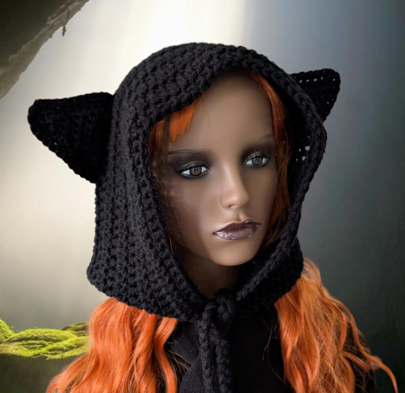 Puede incluir: Sombrero de punto negro con capucha y orejas de gato. La capucha est&aacute; atada al cuello con un cord&oacute;n largo y delgado.