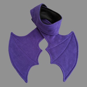 May include: Purple fleece bat wings with a matching neck warmer. The wings are attached to the neck warmer with a seam.