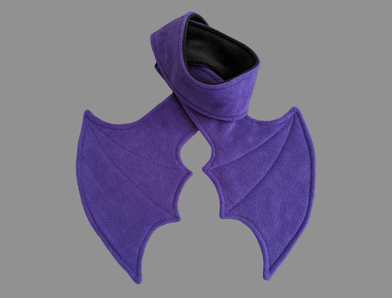 May include: Purple fleece bat wings with a matching neck warmer. The wings are attached to the neck warmer with a seam.