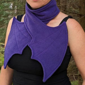 May include: Purple fleece scarf with bat wings. The scarf is worn around the neck and the wings drape over the shoulders.
