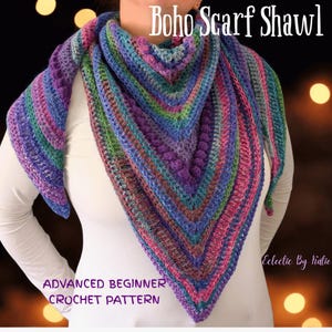 Pu&ograve; includere: Uno scialle a sciarpa Boho all'uncinetto multicolore nei toni del viola, blu, verde e rosa. Lo scialle presenta un motivo a punto strutturato ed &egrave; etichettato come un modello all'uncinetto per principianti avanzati. Il testo sull'immagine recita "Boho Scarf Shawl" e "Eclectic By Katie".