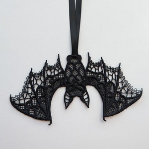 May include: Black lace bat ornament with a hanging loop. The bat is intricately designed with a delicate lace pattern.