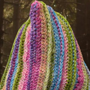 May include: A colourful striped crochet hat with a pointed top. The hat is made with a variety of shades of pink, green, blue, and white yarn.