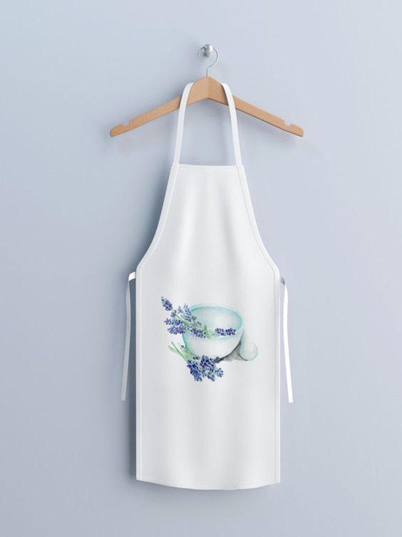May include: White apron with a watercolor design of a light blue bowl and sprigs of lavender. The apron is hanging on a wooden hanger against a light blue wall. The apron has white straps.