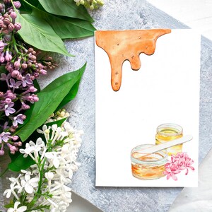 May include: Watercolor illustration featuring a white card with an orange dripping design, jars of wax, a wooden spatula, and pink flowers. Lilac and green leaves are in the background.