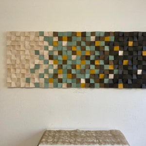 Pu&ograve; includere: Un'opera d'arte da parete realizzata con quadrati di legno in varie tonalit&agrave; di marrone, beige, verde e giallo. I quadrati sono disposti in uno schema geometrico, creando un design moderno e astratto.