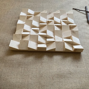 May include: A wooden wall art piece with a geometric design. The piece is made of light wood and has a textured surface.