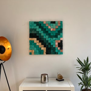 May include: A wall art piece made of wood blocks in shades of green, teal, and pink. The blocks are arranged in a geometric pattern, creating a modern and abstract design.