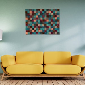 May include: A yellow sofa with a wooden frame sits in front of a light blue wall with a colorful square wall art piece above it.